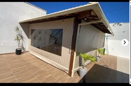 Toldo cortina bege com visor transparente em área coberta
