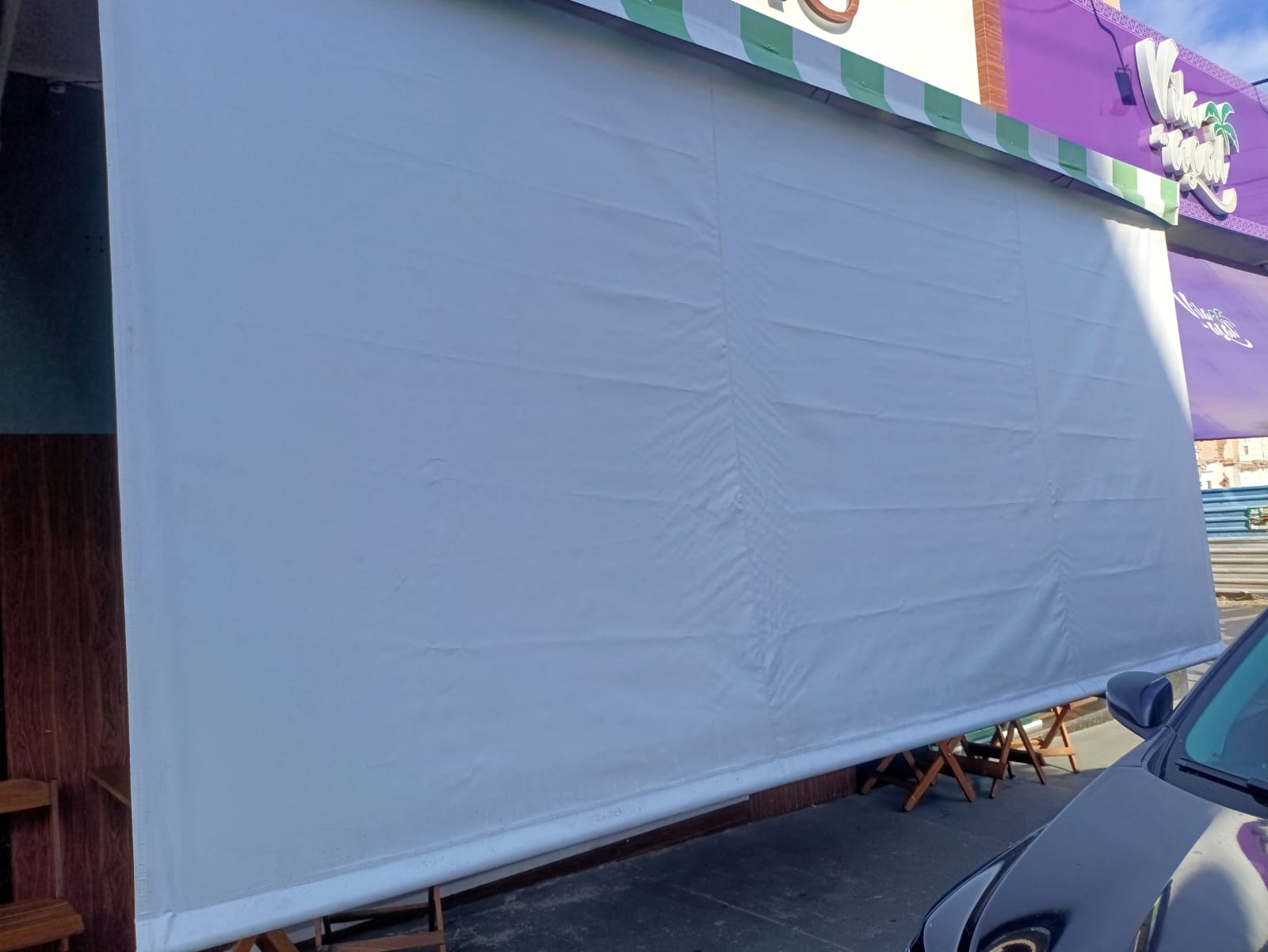 Toldo cortina cinza protegendo a frente de um comércio